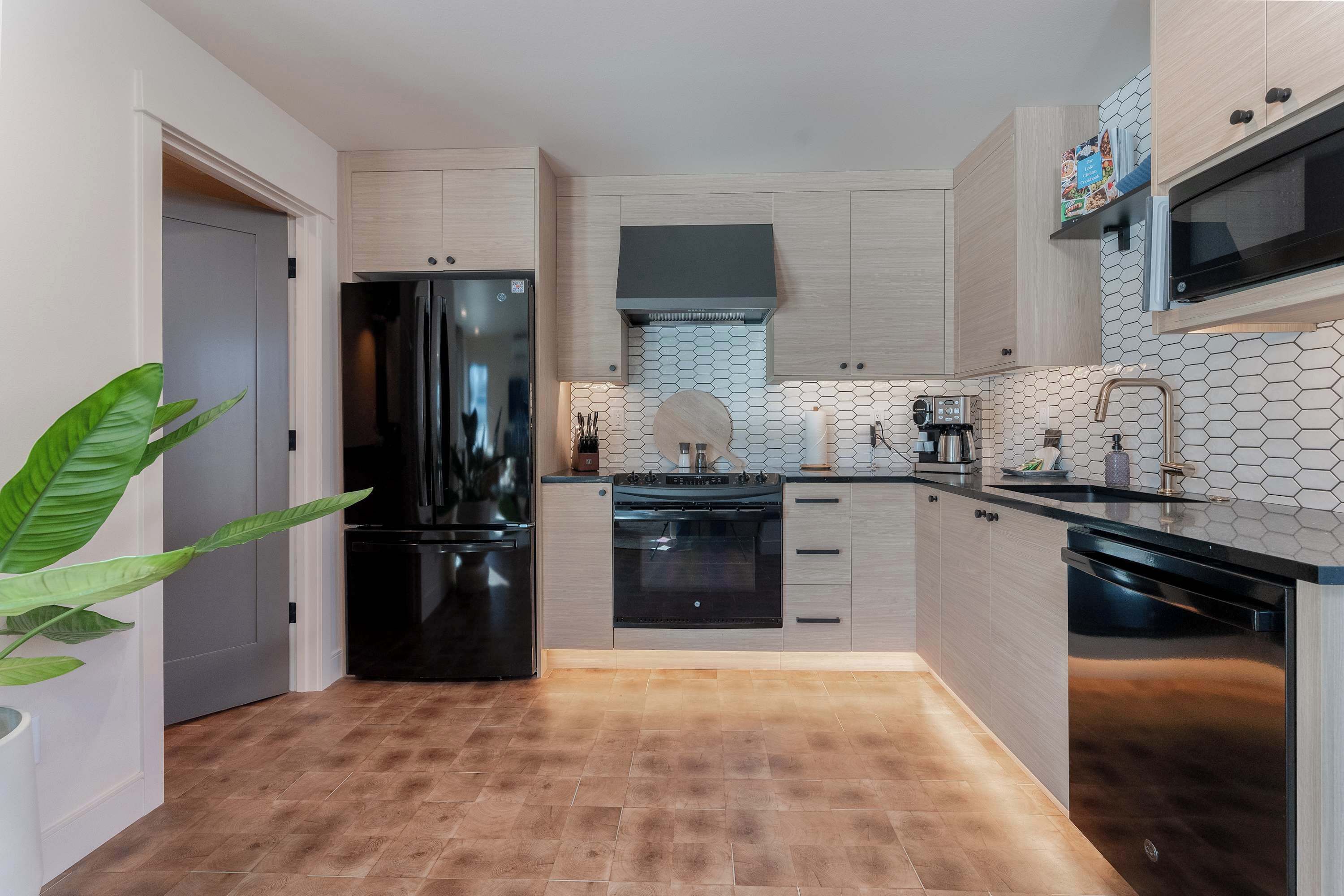 A compact kitchen with a black refrigerator, a stove, and a microwave.