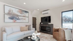 A modern living room with a sofa, armchair, coffee table, fireplace, and artwork on the wall. - Romantic Lakefront Condo F5 + Pool - Wapato Chelan (Manson)
