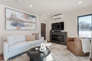 A modern living room with a sofa, armchair, coffee table, fireplace, and artwork on the wall. - Romantic Lakefront Condo F5 + Pool - Wapato Chelan (Manson)