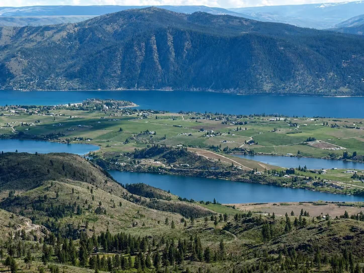 A mountainous landscape with a lake, a small town, and a golf course.