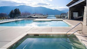 A swimming pool with clear water, surrounded by a stone deck, with mountains in the background. - Romantic Lakefront Condo F5 + Pool - Wapato Chelan (Manson)