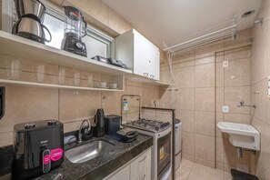 A compact kitchen with a gas stove, a coffee machine, and a built-in oven. - Beach Village #1205 - Sea View by Carpediem (Fortaleza)