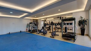 A spacious gym with various exercise equipment, a blue floor, and a ceiling with recessed lighting. - Beach Village #1205 - Sea View by Carpediem (Fortaleza)