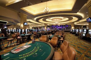 Ein Casino mit mehreren Blackjack-Tischen, Spielautomaten und einer großen Chandelier.