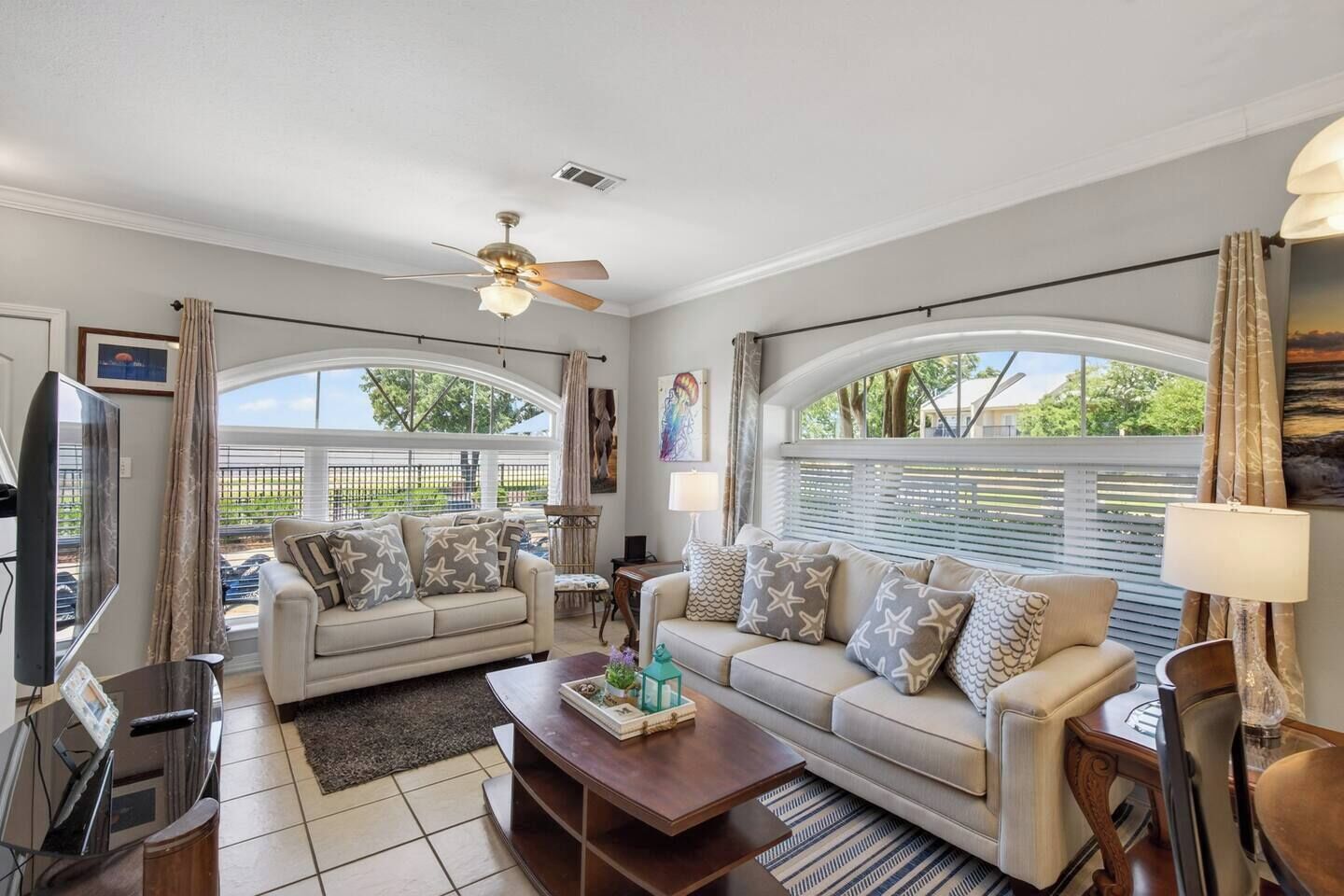A living room with two sofas, a coffee table, a TV, and a ceiling fan.