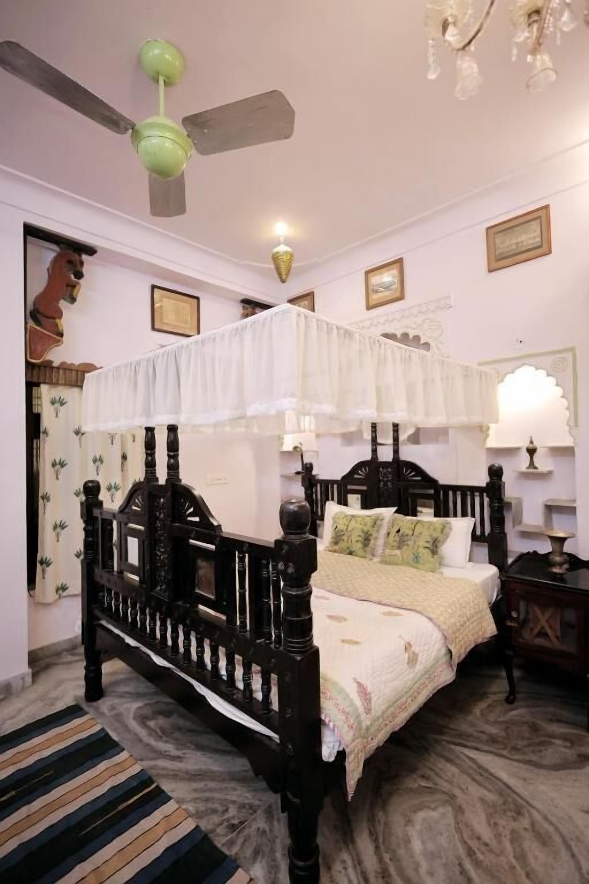 Une chambre à coucher avec un lit à baldaquin, un ventilateur de plafond et un lustre.