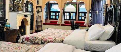 Quarto tradicional com duas camas, lareira e vista pela janela, incluindo um assento vermelho.
