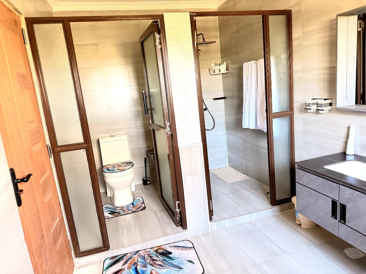A modern bathroom with a glass shower enclosure, a toilet, and a vanity with a mirror.