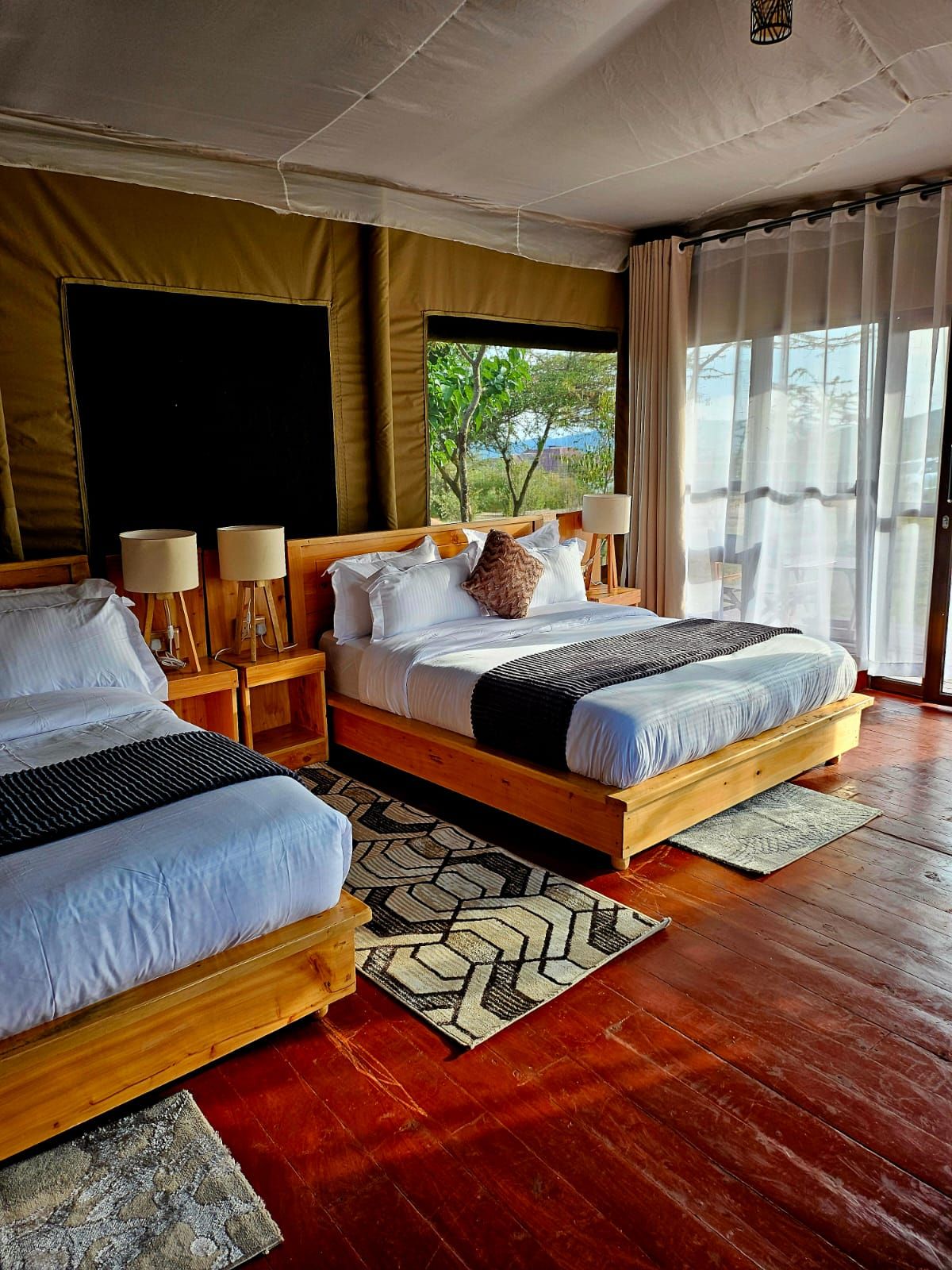 Habitación de hotel con dos camas, un ventanal grande y vistas a zonas verdes.