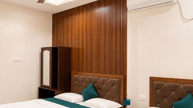 Habitación de hotel con dos camas, ventilador de techo, aire acondicionado y pared de paneles de madera.