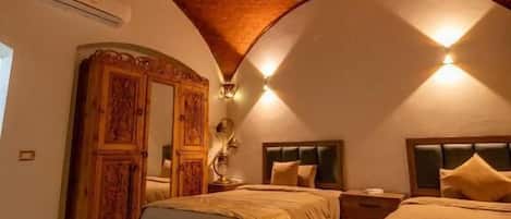 A bedroom with two beds, a patterned rug, and a decorative ceiling.