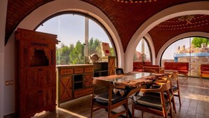A dining area with a wooden table and chairs, arched windows, and a brick ceiling. - B&W Sahara Sky Hotel (Al Bawiti)