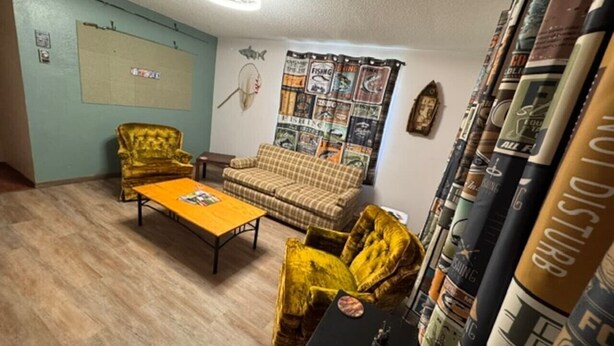 A room with a sofa, two armchairs, a coffee table, and a wall with a fishing-themed tapestry. - Slew Shark Suite Number 4 (Crosby)