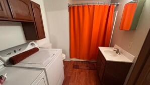 A compact bathroom with a shower curtain, a sink, and a washing machine. - Slew Shark Suite Number 4 (Crosby)