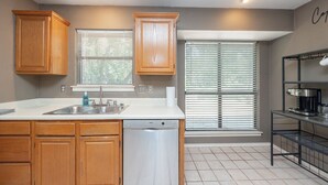 A kitchen with wooden cabinets, a Bosch dishwasher, a sink, and a coffee machine. - Wooded Retreat Minutes from DFW Airport (Flower Mound)