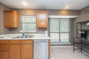 A kitchen with wooden cabinets, a Bosch dishwasher, a sink, and a coffee machine. - Wooded Retreat Minutes from DFW Airport (Flower Mound)
