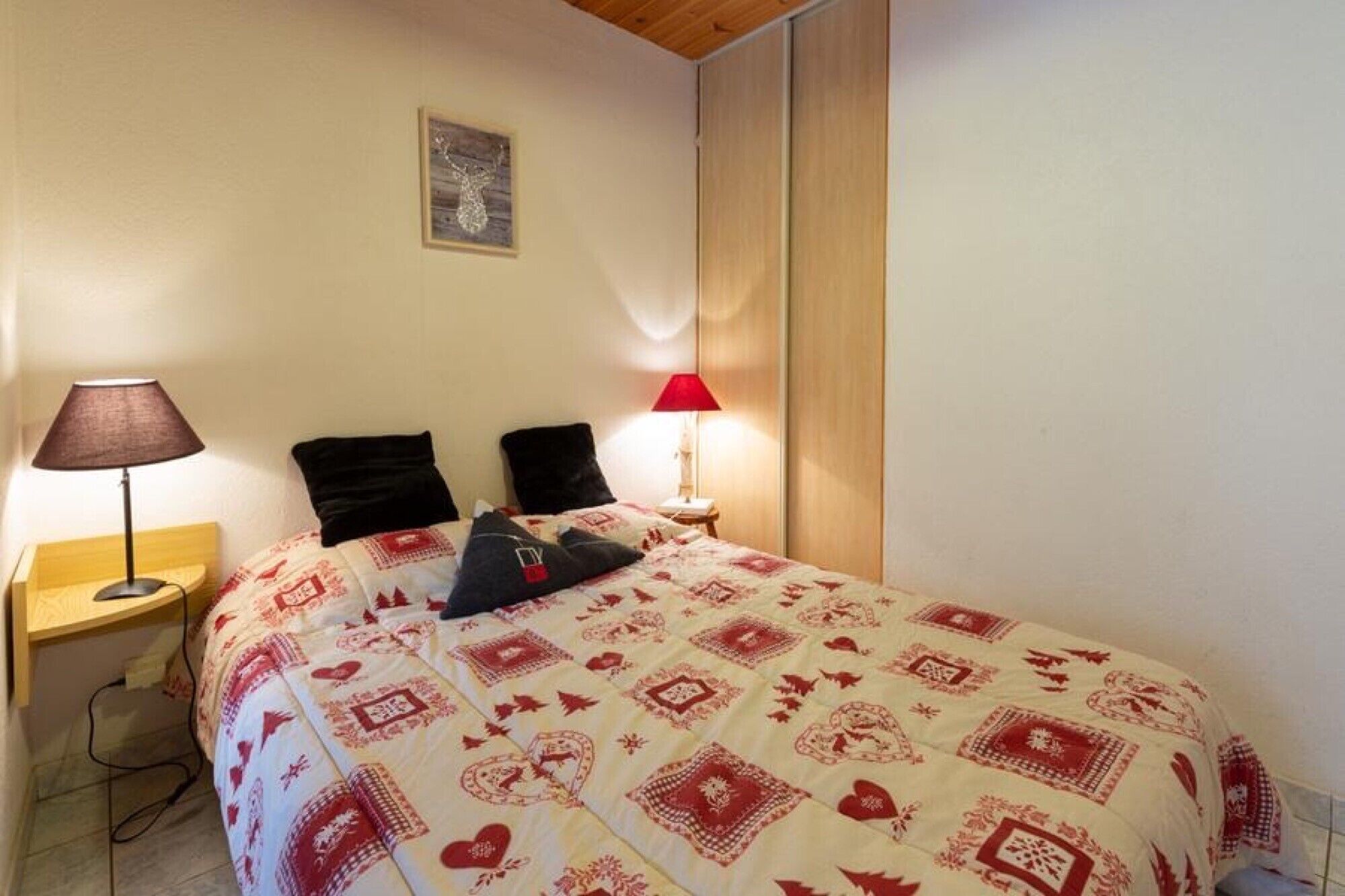 Ein Schlafzimmer mit einem Bett, zwei Nachttischlampen, einem Nachttisch und einem Wandbild.