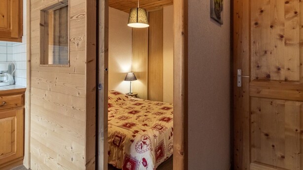 Et trægulv med en seng, en lampe og et vindue.