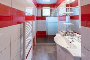 Ein modernes Badezimmer mit einer Duschkabine aus Glas, einem weißen Waschbecken und einem Handtuchhalter.