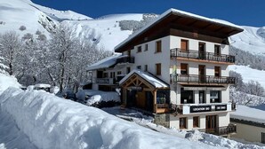 A multi-story hotel with a ski location sign, surrounded by snow-covered trees and mountains. - Les Balcons de St So Apartment 1 – Mountain View, 2 Bedrooms, Near Slopes (Saint-Sorlin-d'Arves)