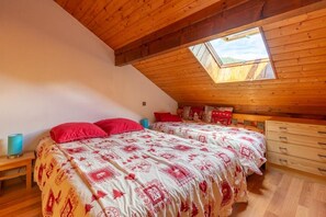 Ein Schlafzimmer mit zwei Betten, einem Oberlicht, Holzbalken an der Decke und einem Schminktisch.