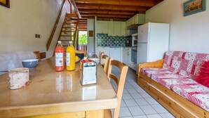Un'area pranzo con tavolo in legno, sedie e una cucina sullo sfondo.
