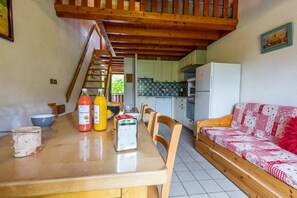 Ein Essbereich mit einem Holztisch, Stühlen und einer Küche im Hintergrund.