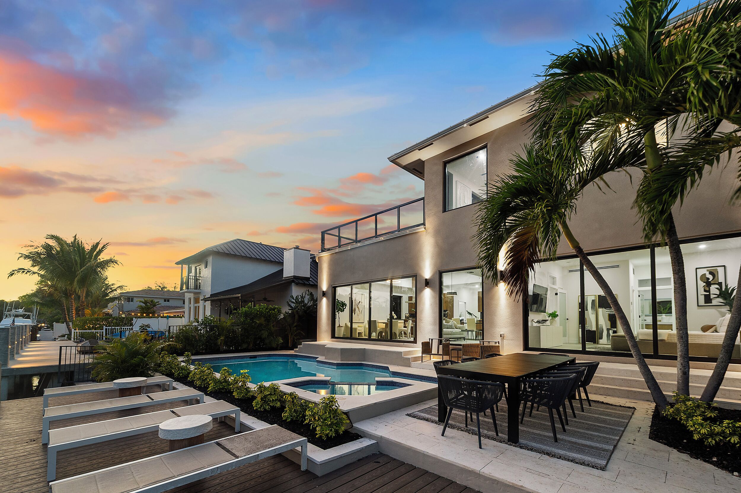 Ein modernes Haus mit Pool, Sitzgelegenheit im Freien und einem Balkon mit Blick auf den Pool.