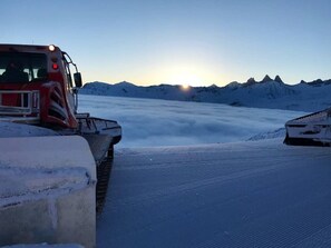 A snow-covered landscape with a red vehicle and a partially visible building. - Les Balcons de St So Apartment B – 3 Bedrooms, Ski-In/Ski-Out, Sleeps 8 (Saint-Sorlin-d'Arves)
