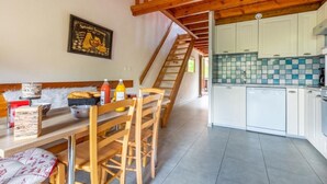 Una stanza accogliente con un tavolo da pranzo in legno, sedie, una panca e una scala che conduce a un piano superiore.