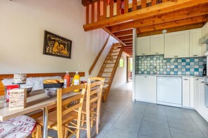 A cozy room with a wooden dining table, chairs, a bench, and a staircase leading to an upper level. - Les Balcons de St So Apartment B – 3 Bedrooms, Ski-In/Ski-Out, Sleeps 8 (Saint-Sorlin-d'Arves)