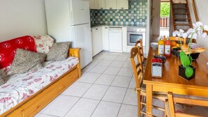A compact living space with a kitchenette, a dining area, and a sofa. - Les Balcons de St So Apartment C – 8 Guests, Ski-In/Ski-Out, Mountain View, 3 Bedrooms (Saint-Sorlin-d'Arves)