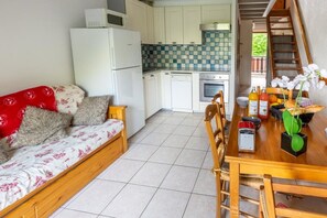 A compact living space with a kitchenette, a dining area, and a sofa. - Les Balcons de St So Apartment C – 8 Guests, Ski-In/Ski-Out, Mountain View, 3 Bedrooms (Saint-Sorlin-d'Arves)