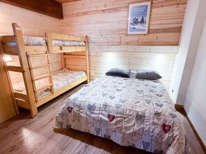 Ein Zimmer mit einem Etagenbett und einem Einzelbett, beide mit gemusterten Bettdecken.