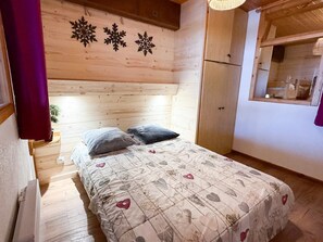 A wooden room with a bed, a window, and a door. - Les Balcons de St So Apartment D – Spacious, Sleeps 12, Near Slopes & Shops (Saint-Sorlin-d'Arves)