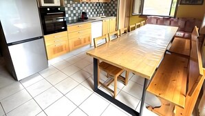 Una cucina moderna con mobili in legno, un ampio tavolo da pranzo e un forno integrato.