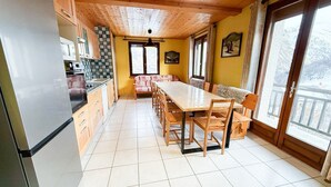 Una cucina con zona pranzo, soffitto in legno e ampie finestre.