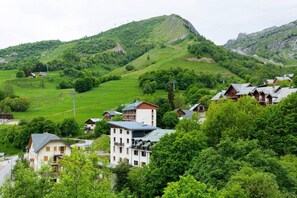 Ein Dorf an einem Hügel mit traditioneller Bebauung, eine freie Straße und ein Berg im Hintergrund.