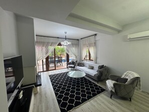 A living room with a sofa, armchair, TV, and a patterned rug. - Deluxe Villa with Private Pool (Antalya)