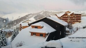 A snow-covered mountain resort with chalet-style buildings, including a prominent wooden structure with a sloped roof and a smaller building with a flat roof.