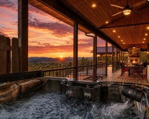 A hot tub area with a wooden deck, a fire pit, and a view of the sunset. - Mack Mountain Lodge (Kirby)