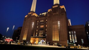 Ein großes Industriegebäude mit zwei markanten Schornsteinen, einem zentralen Eingang und einem flachen Dach.