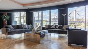 Ein modernes Wohnzimmer mit einer Sofagarnitur, einem Couchtisch und großen Fenstern mit Blick auf eine Brücke.