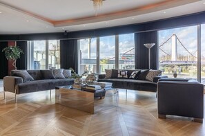 Ein modernes Wohnzimmer mit einer Sofagarnitur, einem Couchtisch und großen Fenstern mit Blick auf eine Brücke.