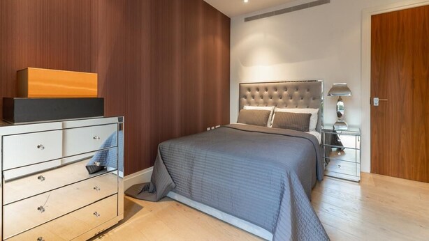 Ein Schlafzimmer mit Bett, Schminktisch, Nachttisch und Holztür.