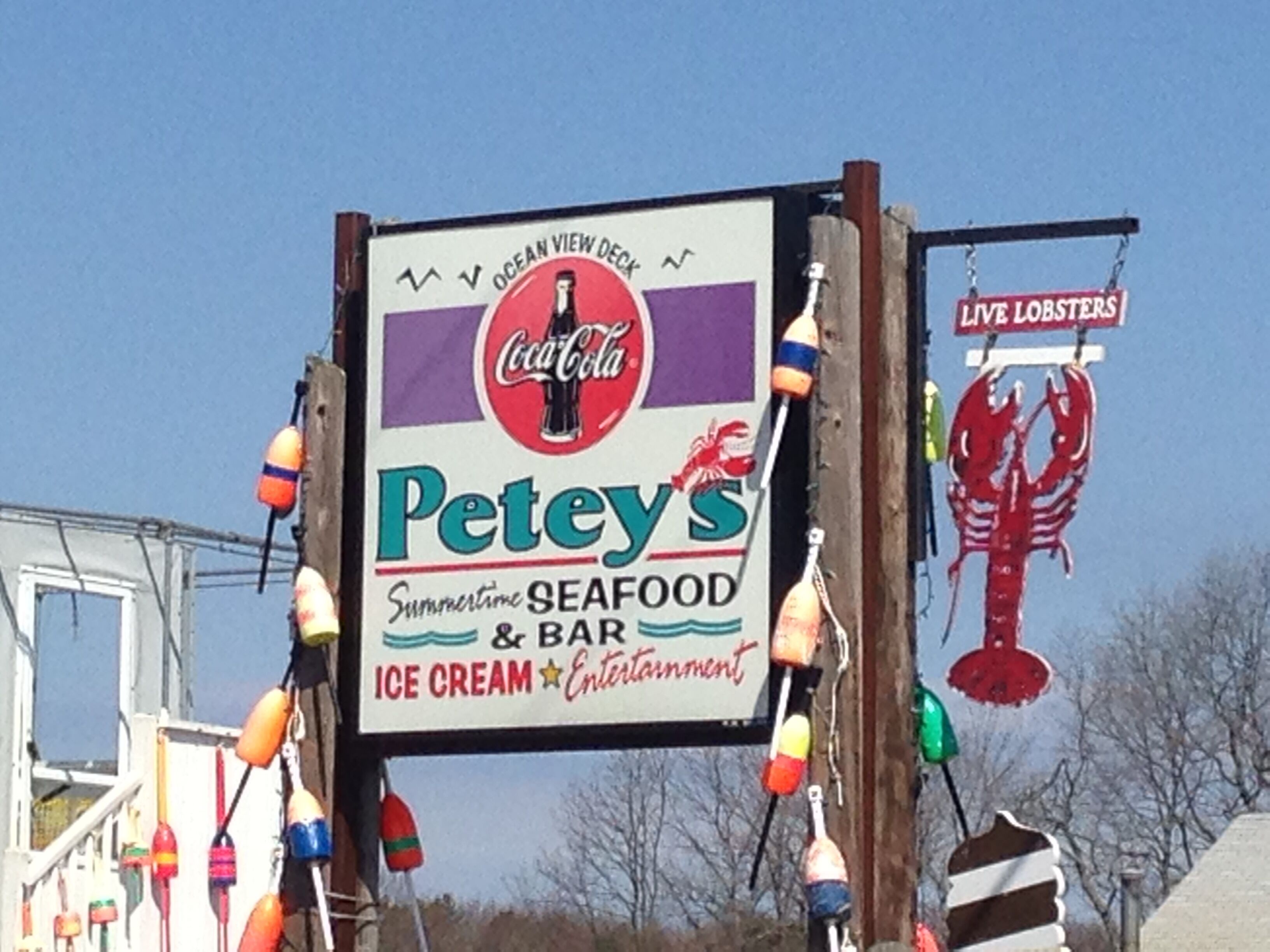 Naamplaatje voor 'Pete's Seafood & Bar' met een Coca-Cola logo, dat een visrestaurant en bar aangeeft met ijs en entertainment.