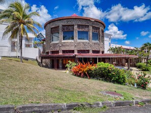 A two-story building with a stone facade, a red roof, and a covered outdoor area with plants. - Studio, Pool, and Beach (Saint-François)