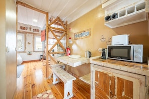 A rustic kitchen with wooden beams, a white countertop, a microwave, and a wooden bench. - GuestReady - Modern Duplex in Lisbon (Lisbon)