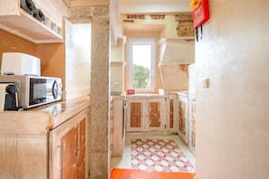 A narrow kitchen with a microwave, cabinets, and a window. - GuestReady - Modern Duplex in Lisbon (Lisbon)