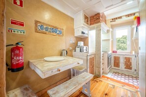 A rustic kitchen with a wooden countertop, a fire extinguisher, and a window with a view of greenery. - GuestReady - Modern Duplex in Lisbon (Lisbon)